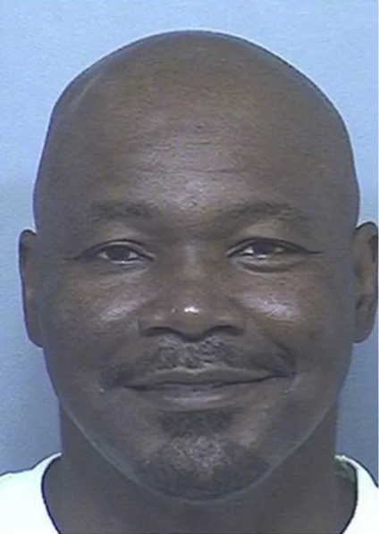 A balding Black man with a goatee smiles at the camera.